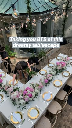 a long table is set up with flowers and gold plates for an outdoor wedding reception