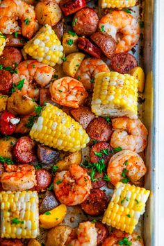 shrimp, corn on the cob and potatoes in a baking pan with parsley