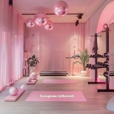 a pink room with yoga mats and exercise balls