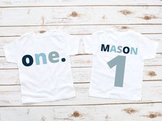 two t - shirts with the words one, mason and 1 printed on them sitting next to each other