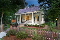 a small white house sitting next to a wooden fence