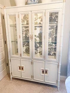 a white china cabinet with glass doors and drawers