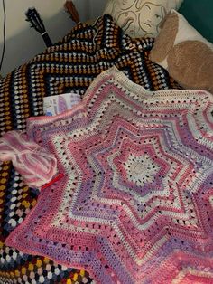 a crocheted blanket is laying on a bed with a teddy bear next to it