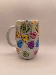 this is a coffee mug with hearts and words painted on it that says kiss me, smile