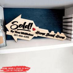 a wooden sign with the words sold on it in black and white, sitting on top of a shelf