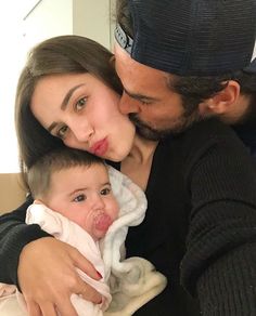 a man and woman holding a baby with their tongue out in front of the camera