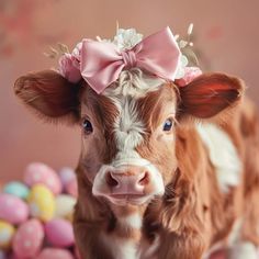 a brown and white cow with a pink bow on it's head next to some eggs