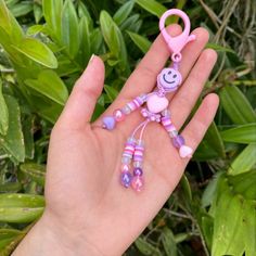 a person's hand holding a pink and purple beaded monkey keychain