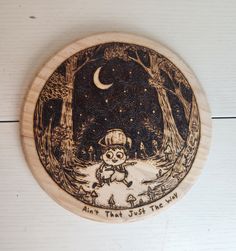 a wooden plate with an image of a snowman in the woods on it's side