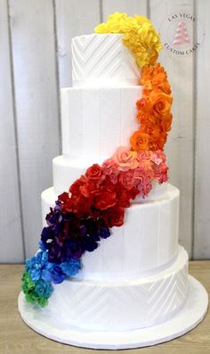 a multi - tiered white cake with colorful flowers on top