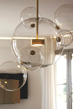 three clear glass orbs hanging from a brass chandelier in a living room