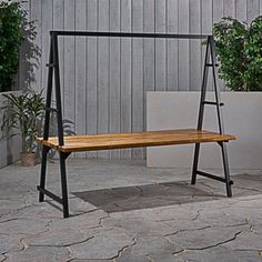 a wooden bench sitting on top of a stone floor next to potted planters