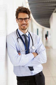 a male doctor is standing with his arms crossed and looking at the camera while wearing a stethoscope