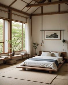 a large bed sitting in a bedroom next to two windows and a potted plant