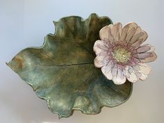 a large leaf shaped bowl with a flower in it's center and two petals on the side