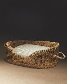 a wicker basket with a white pillow on the bottom is shown in front of a black background