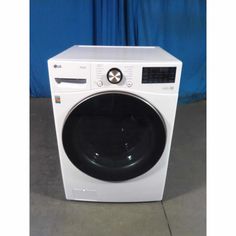 a white washer sitting on top of a floor next to a blue wall with curtains