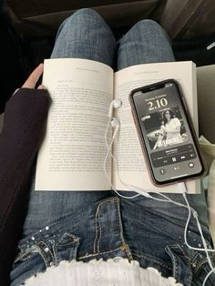 an open book sitting on top of a person's lap next to headphones