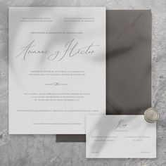 an elegant wedding suite with grey and white accents is displayed on a marble surface, along with a wax seal