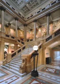 the inside of an old building with marble floors and stairs, lights and chandeliers