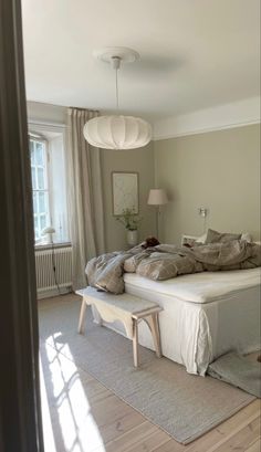 a bed sitting on top of a wooden floor next to a window in a bedroom