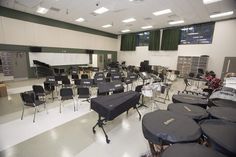 an empty classroom filled with black chairs and lots of desks covered in black covers