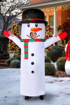 a man in a snowman costume standing next to a house with christmas lights on it