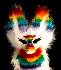 a multicolored mask with feathers on it's face is shown in front of a black background