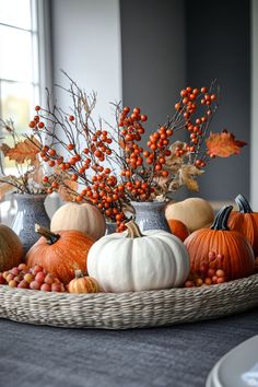 a basket filled with lots of different types of pumpkins and berries on top of a table