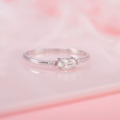 a diamond ring sitting on top of a pink surface