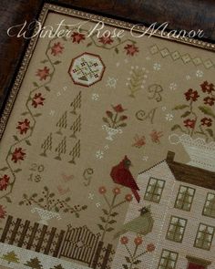 a cross - stitch pattern with a house and flowers on it