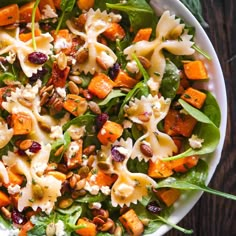 a white bowl filled with pasta salad topped with cranberries and pecori