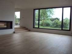 an empty living room with wood floors and large windows that look out onto the yard