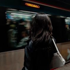 a woman is waiting for the subway to arrive