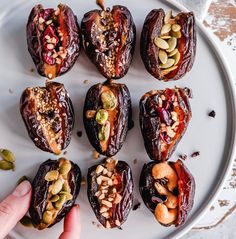 someone is picking up some fruit on a plate with nuts and seeds in it to eat