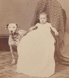 an old black and white photo of a young child with a dalmatian dog