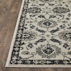 a white rug with black and grey designs on the bottom, sitting on a wooden floor