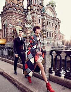 two people standing on the side of a bridge next to a building with a clock tower