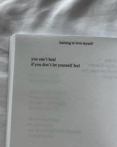 an open book sitting on top of a bed next to a white sheet with the words you can't heal if you don't let yourself feel