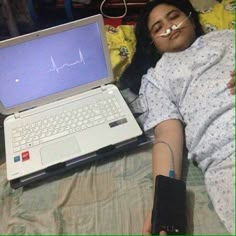 a woman laying in bed next to a laptop computer