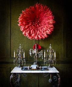 a table topped with a vase filled with flowers and candles next to a wall mounted chandelier