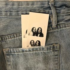 two pictures are placed in the back pocket of a pair of blue jeans, which is showing three women's faces