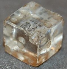 a close up of a dice on a gray surface with small white dots around it