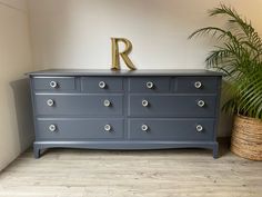 a dresser with the letter r on it and a potted plant in front of it