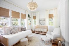 a baby's room with white furniture and large windows