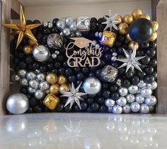 a graduation balloon wall is decorated with balloons and stars in black, gold and silver colors