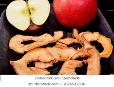 an apple and some sliced up apples on a black plate with other food items around it