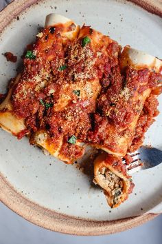 a white plate topped with lasagna covered in sauce and parmesan cheese