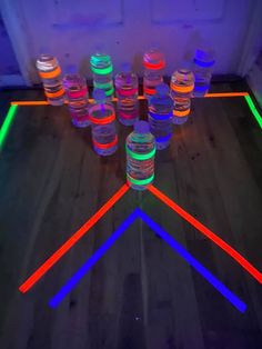 neon lights are arranged in the shape of a triangle on a wooden floor with water bottles