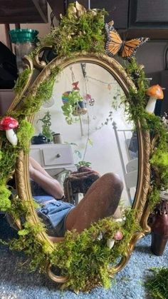 there is a mirror with moss growing on it and a person sitting in the reflection